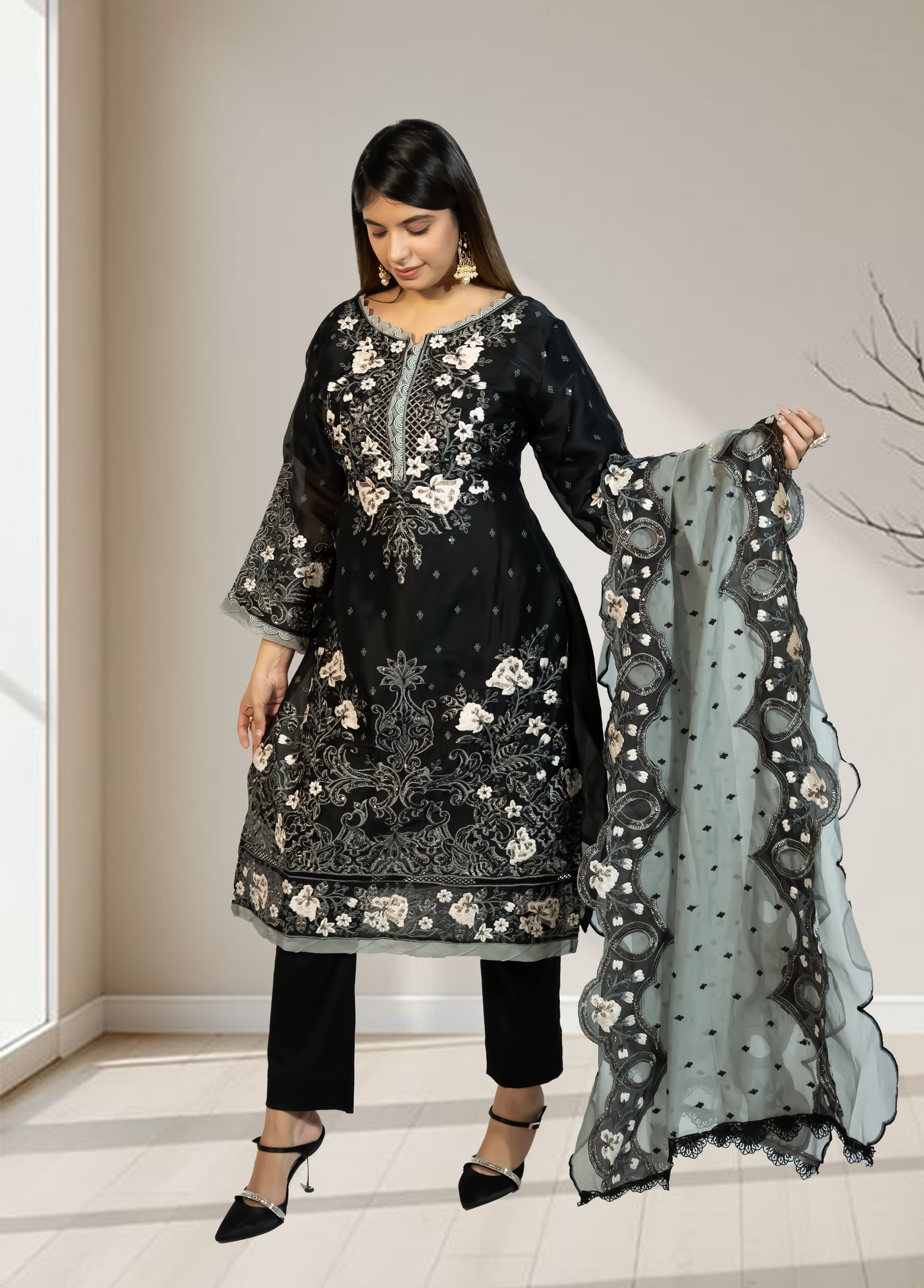 Woman wearing a black embroidered outfit with a matching dupatta in a neutral setting