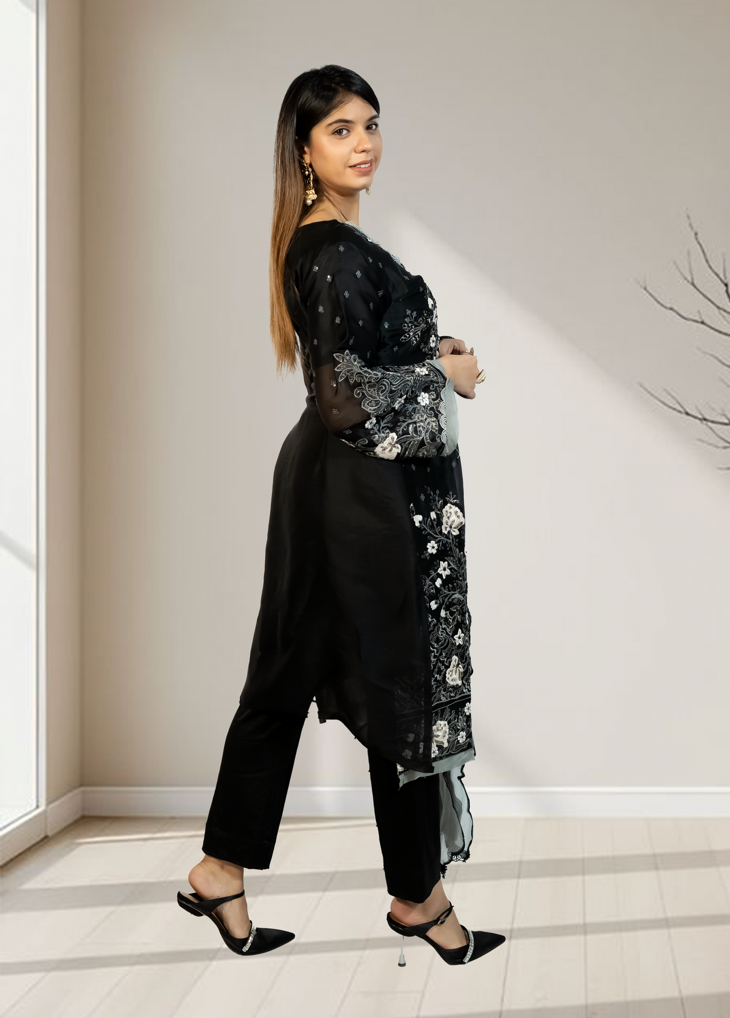 Woman wearing a black outfit with floral embroidery in an indoor setting