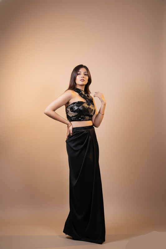 Woman wearing a black lace top and long black skirt against a beige background