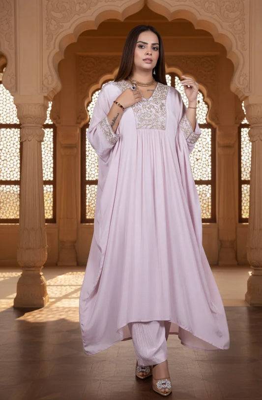 Woman in a light pink traditional outfit with white embroidery standing in an ornate architectural setting.