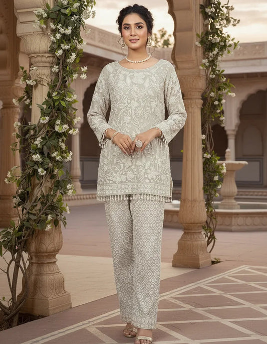 Woman in a traditional outfit standing in an ornate courtyard with floral decorations.