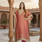 Woman in traditional pink and gold outfit standing in a decorative courtyard.