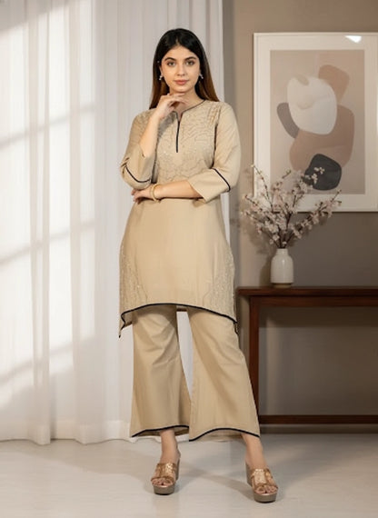 Woman wearing a beige kurta with palazzo pants in a well-lit room.
