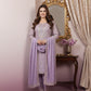 Woman in a lavender traditional outfit standing in front of a decorative mirror.