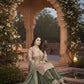 Woman in traditional attire sitting under a floral archway