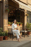 Woman sitting outside a cafe with plants and tables around her