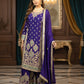 Woman in a traditional embroidered outfit with a purple shawl in an elegant room.