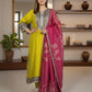 Woman wearing a yellow and pink traditional outfit in a room with a mirror and shelves.