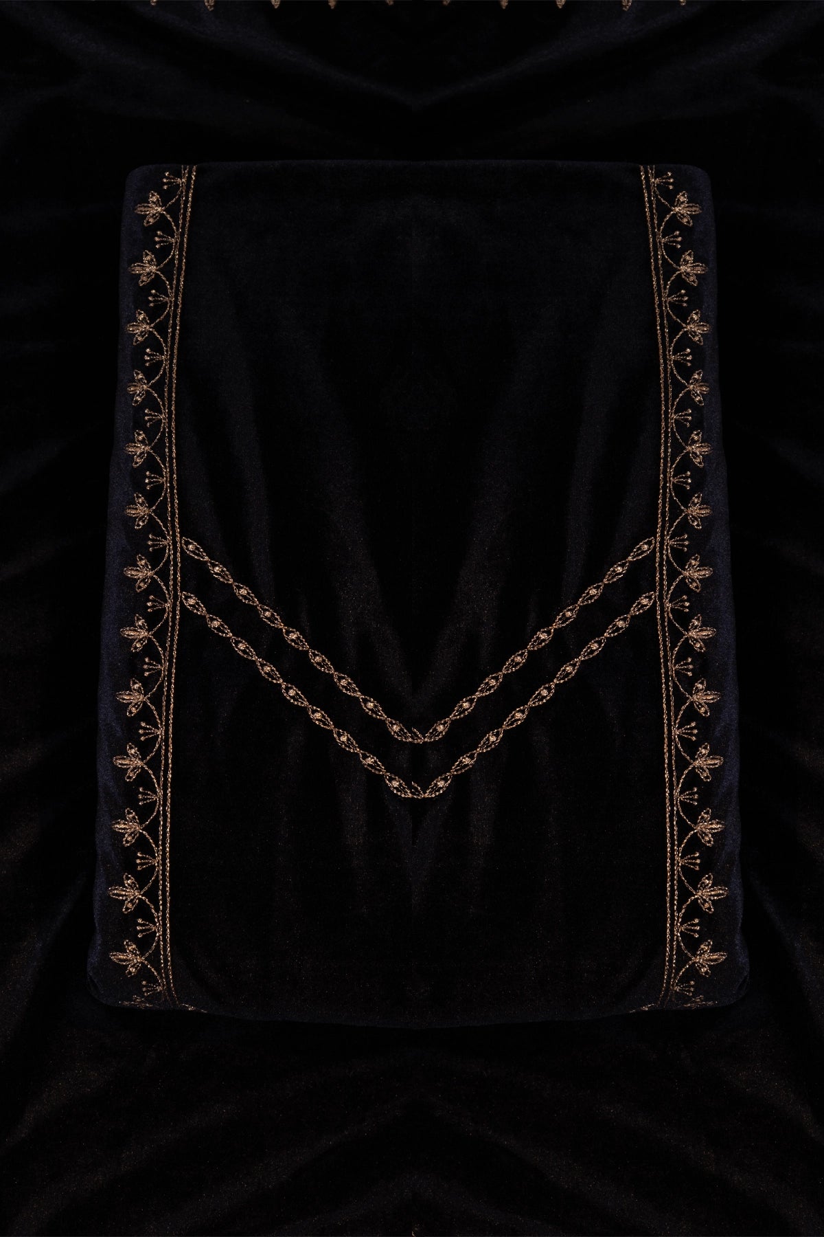 Black velvet fabric with gold embroidery on a dark background