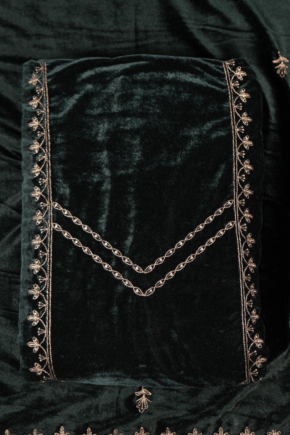 Dark green velvet fabric with gold embroidery on a dark background