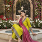 Woman in a yellow and pink traditional outfit sitting by a fountain with floral decorations.