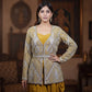 Woman wearing a traditional outfit with a patterned top and yellow pants in an indoor setting.