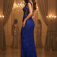 Woman in a blue evening gown standing in a lavishly decorated room with chandeliers.