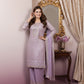 Woman in a lavender traditional outfit standing in front of a decorative mirror.