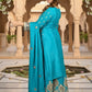 Woman in a turquoise saree with floral decorations in the background