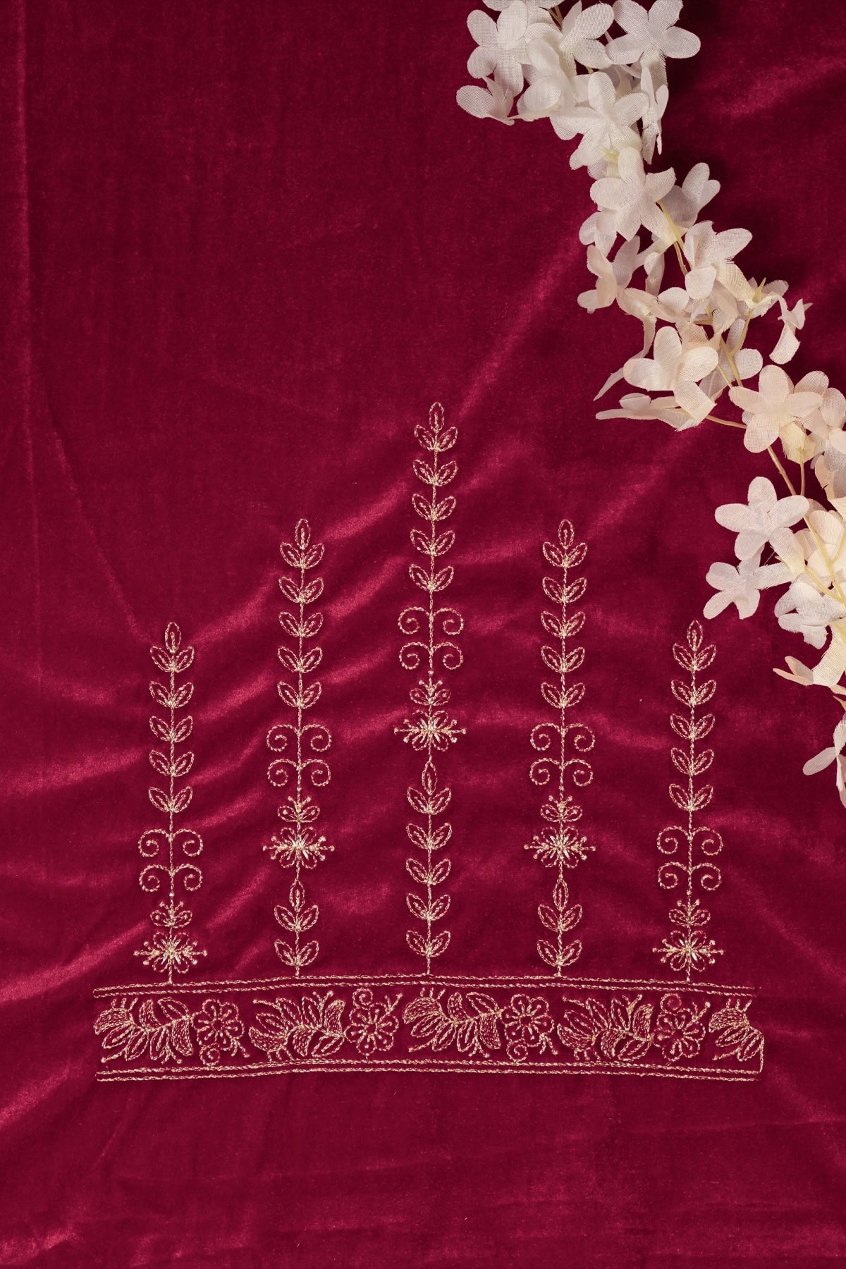 Decorative red fabric with white floral embroidery and a branch of white flowers on a matching red background.