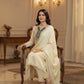 Woman in a cream traditional outfit sitting on a wooden chair in an elegant room.