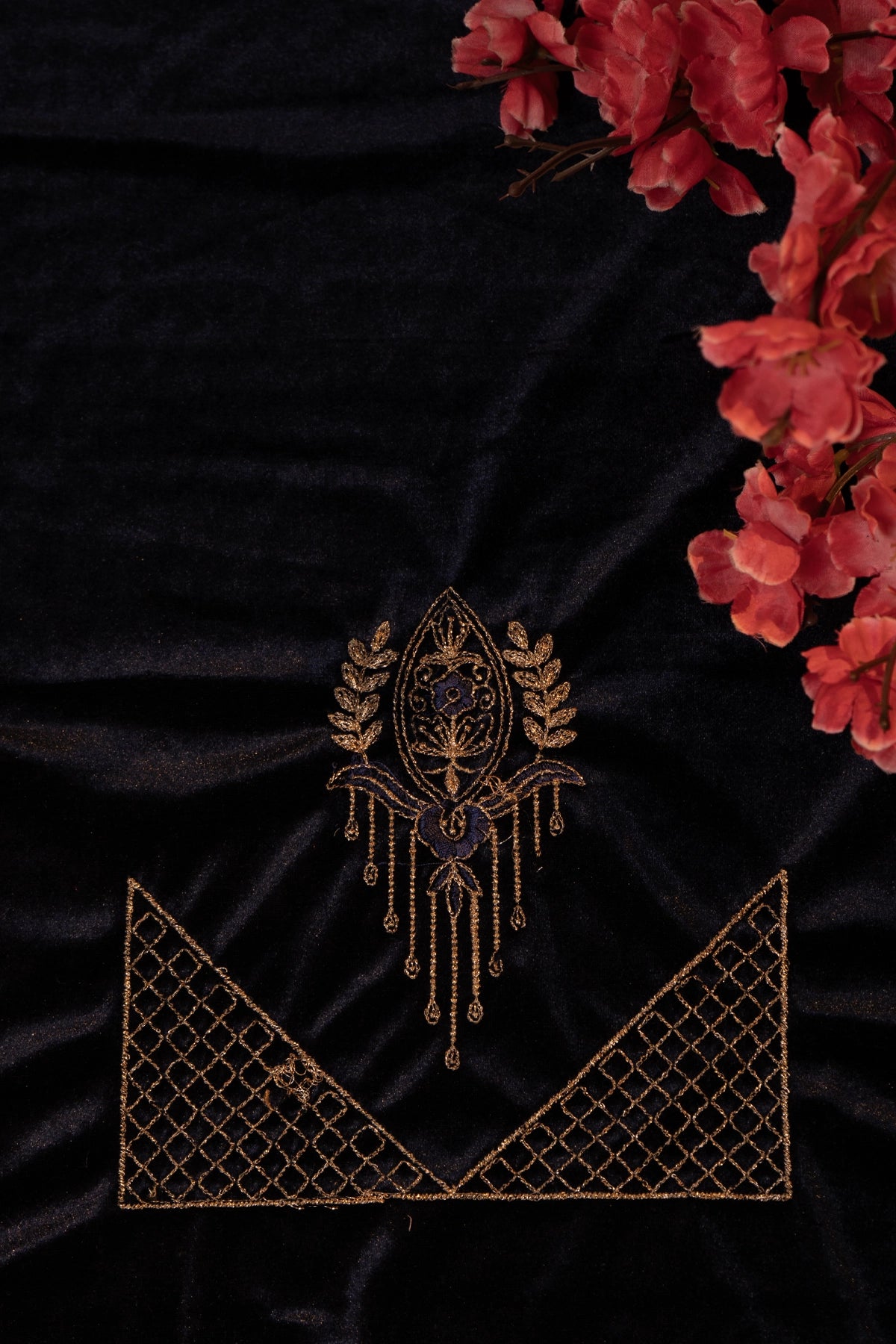 Black fabric with gold embroidery and red flowers on a dark background