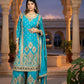 Woman in a blue embroidered traditional outfit standing in an architectural setting.
