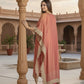Woman in a pink saree with gold border standing in an architectural setting