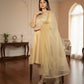 Woman in a light yellow traditional outfit standing in a well-lit room with wooden flooring and decorative elements.