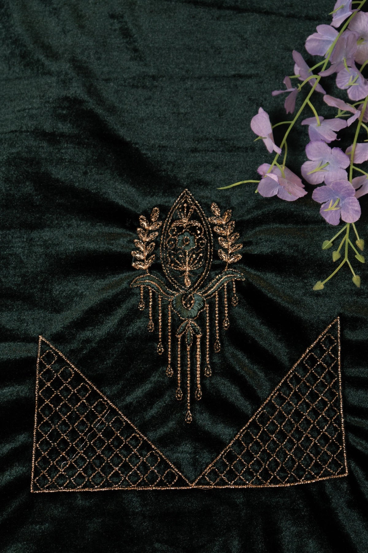 Decorative brooch on a dark green fabric background with purple flowers.