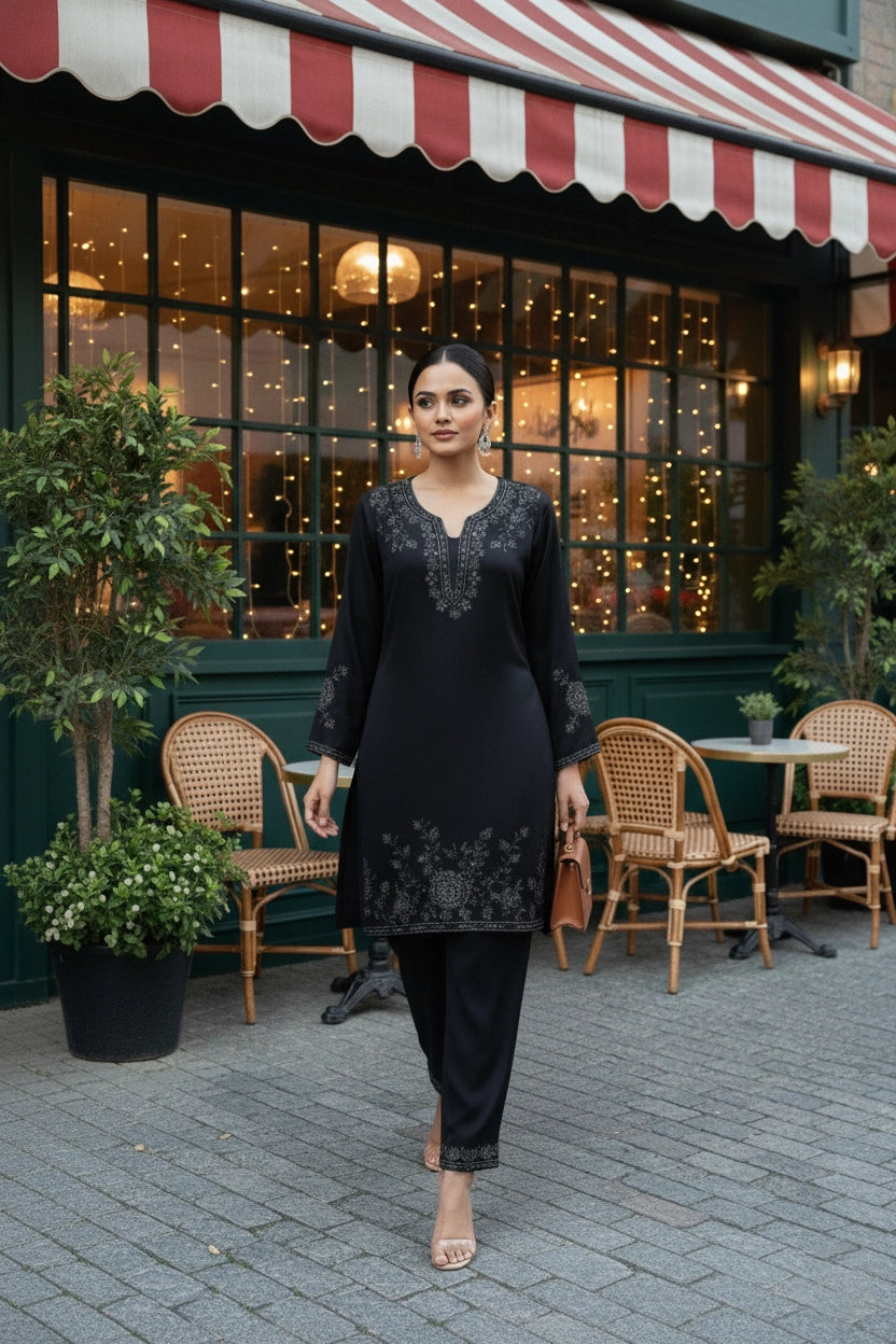 Woman in a black outfit standing in front of a restaurant with a striped awning.