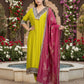 Woman in a green dress with a pink dupatta standing in a garden with flowers and water feature.