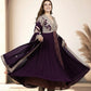 Woman wearing a long purple dress with floral patterns in an indoor setting