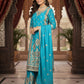 Woman in a turquoise traditional outfit with intricate patterns in an ornate setting.