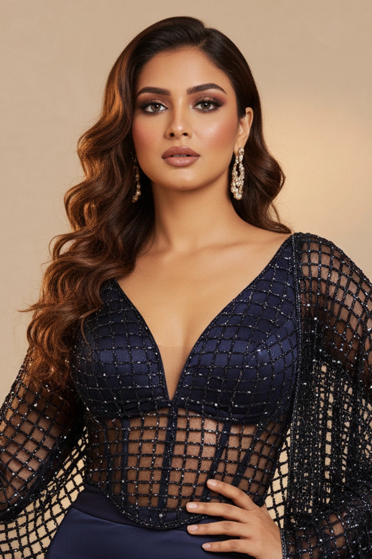 Woman wearing a navy blue dress with sheer sleeves against a beige background