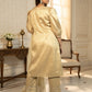Woman in a beige traditional outfit standing in an elegant room with decorative elements.