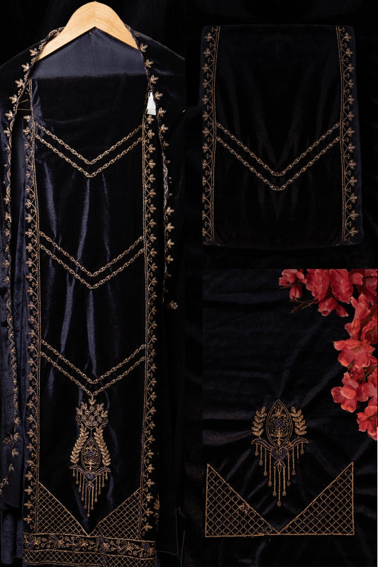 Black velvet garment with gold embroidery on a hanger against a dark background.