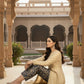 Woman in traditional attire sitting in a courtyard with architectural beauty in the background