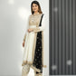 Woman wearing a traditional outfit with a white and black design against a gray curtain background