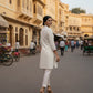 Woman in a white outfit walking on a street with yellow buildings in the background