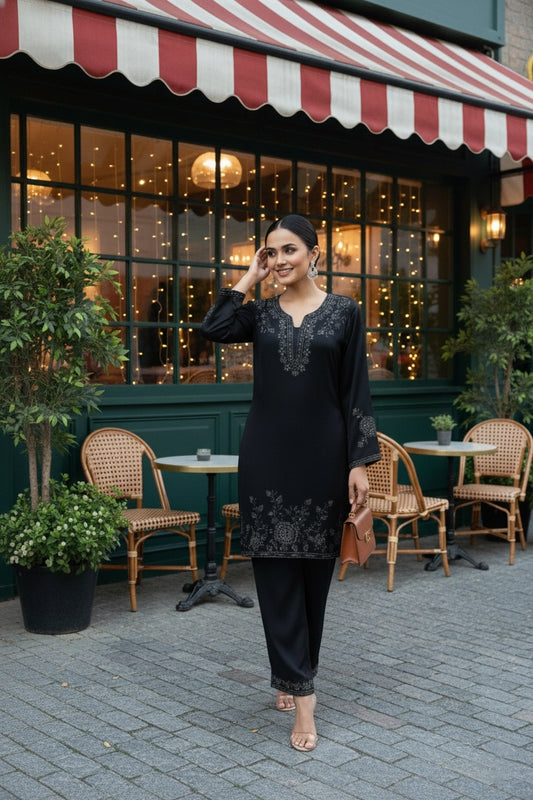 Woman in a black outfit standing outside a restaurant with a striped awning.