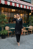 Woman in a black outfit standing outside a restaurant with a striped awning.