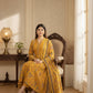 Woman in a yellow traditional outfit sitting on a chair in a well-lit room.