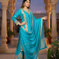 Woman in a blue traditional outfit standing in an architectural setting with plants.