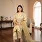 Woman in a beige traditional outfit sitting in a well-furnished room.