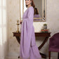 Woman in a lavender saree standing in front of a mirror in a room with decorative elements.