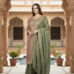 Woman in a green saree standing in an ornate architectural setting with a pool in the background.