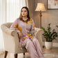 Woman in a pink traditional outfit sitting on a chair in a well-decorated room.