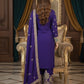 Woman in a purple traditional outfit standing in an elegant room with ornate decor.