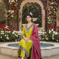 Woman in a yellow outfit with a pink dupatta sitting in a decorated garden.