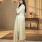 Woman in a white traditional outfit standing in a well-lit room with decorative elements.