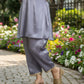 Person wearing a light purple outfit with gold accents in a garden setting