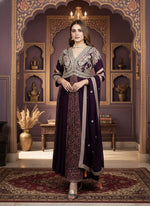 Woman in a traditional outfit standing in an ornate room with decorative walls and furniture.