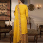 Woman in a yellow traditional outfit with floral patterns in a decorated room.